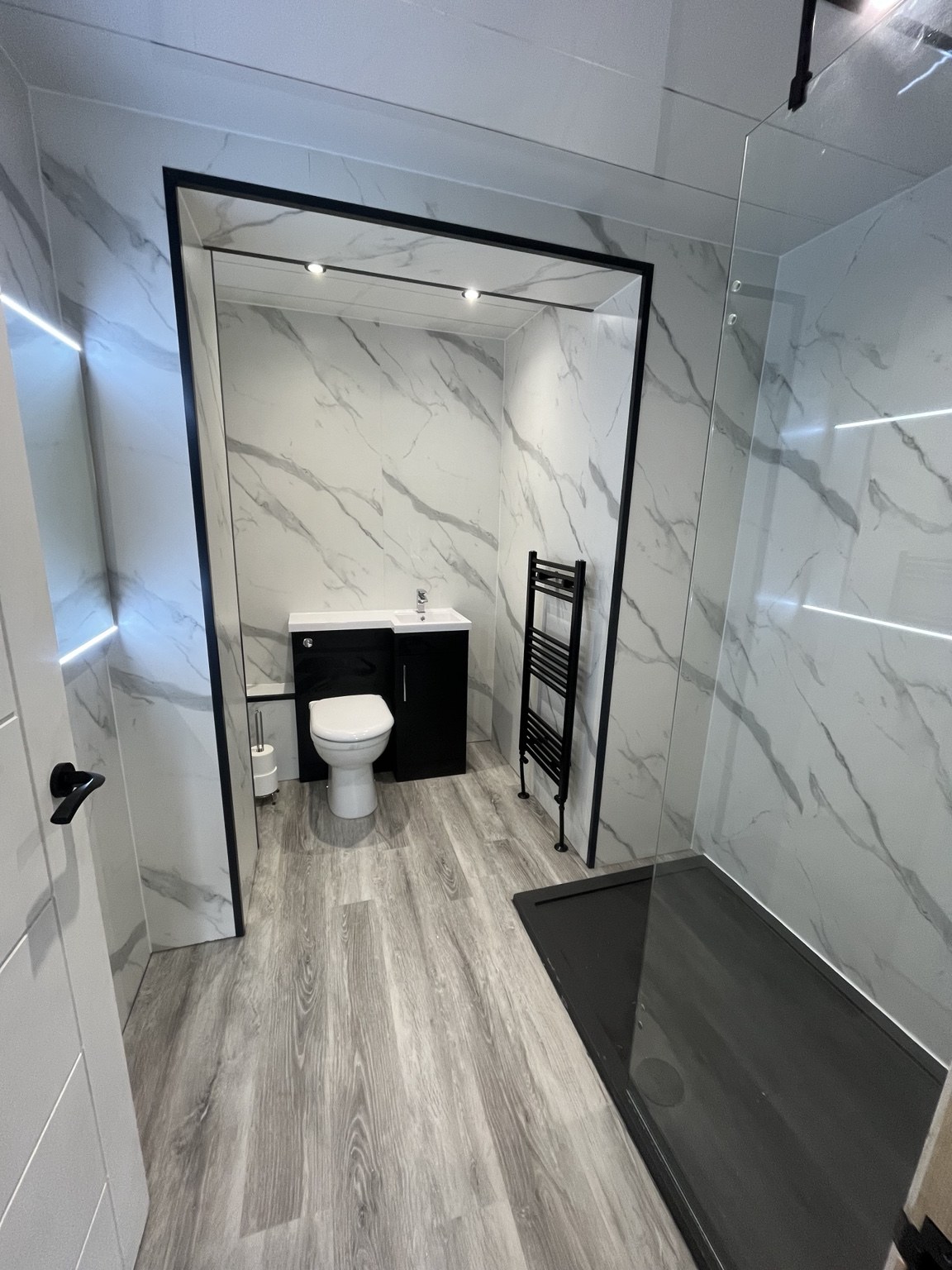 Bathroom with marble-effect wall panels, dark vanity and black towel radiator