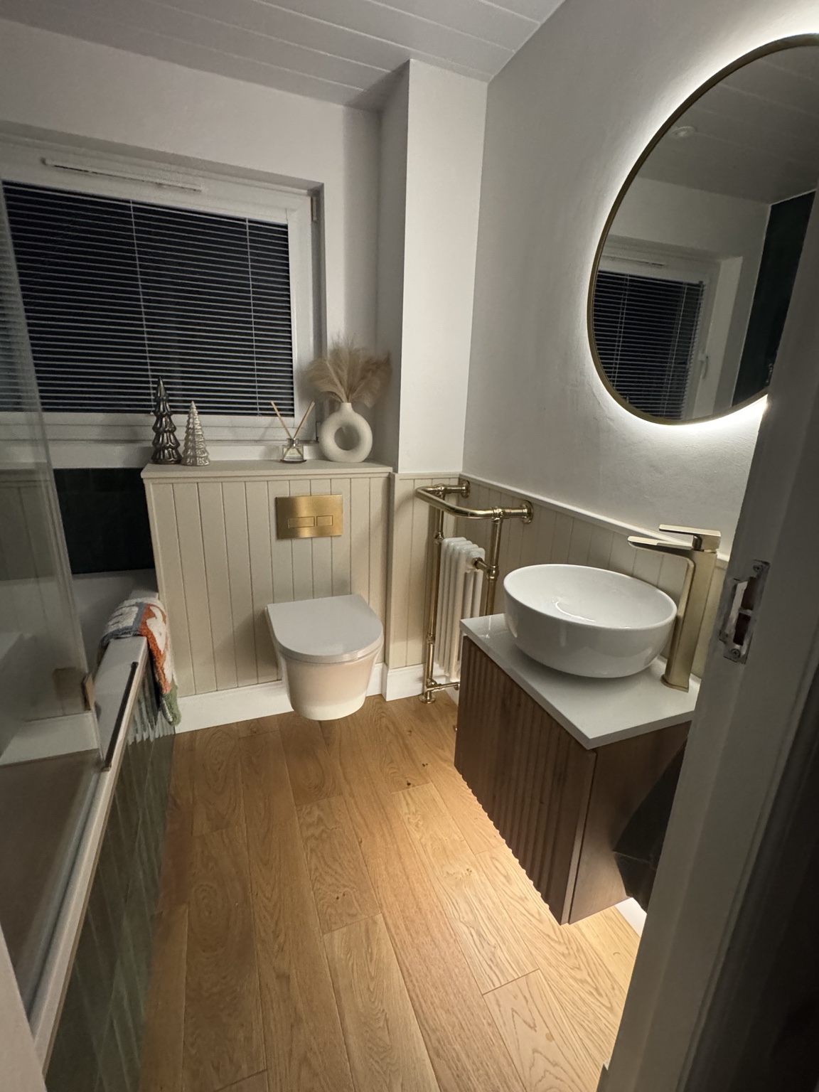 Completed bathroom with illuminated oval mirror, brass fittings and fluted vanity