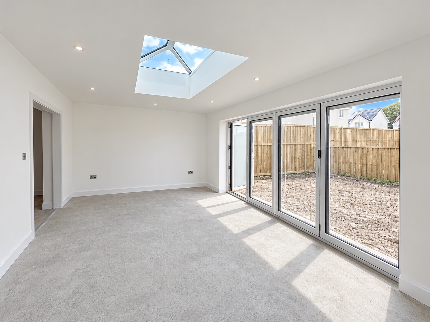 Bright extension interior with white walls, a roof lantern and folding glazed doors